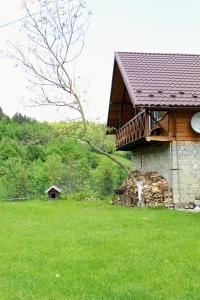 a building with a deck on the side of a field at Багрівчанка in Yaremche