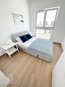 a white bedroom with a bed and a window at Apartamenty Bałtyckie - Luxoro Park in Ustka