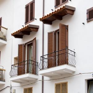 a white building with brown shutters and balconies at A Mos Veure B&B in Alghero