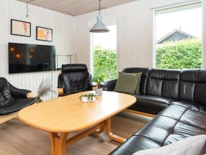 a living room with a black leather couch and a table at 9 person holiday home in Juelsminde in Sønderby