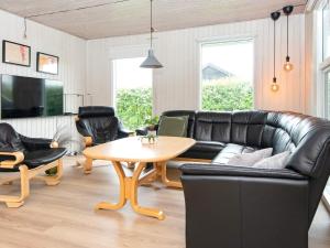 a living room with a black leather couch and a table at 9 person holiday home in Juelsminde in Sønderby