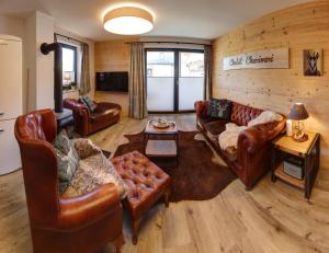 a living room with leather couches and a table at Chalet Charivari Inzell mit Whirlpool, Sauna & Garten in Inzell