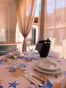 una mesa con un mantel con platos y copas de vino en Casa Posidonia - Vulcano Blu, en Vulcano