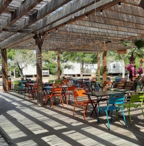 eine Gruppe von Tischen und Stühlen unter einer hölzernen Pergola in der Unterkunft MobilHome de Charlotte - Camping La Falaise 4 étoiles in Narbonne-Plage