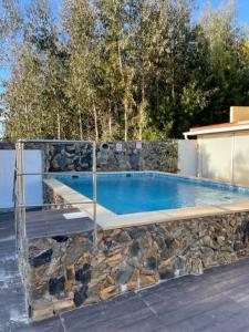 una piscina con una pared de piedra junto a una carga de carga de energía eléctrica en Casa Pejão Do Paraíso, en Castelo de Paiva