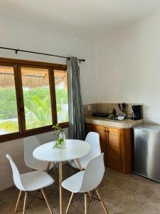 tavolo e sedie bianchi in cucina con finestra di La Casa del Sol Holbox a Isola Holbox