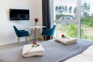 een kamer met een bed met 2 handdoeken en een tafel met stoelen bij Nowoczesne apartamenty Jezioro Ukiel Zatoka Miła Plaża Miejska in Olsztyn