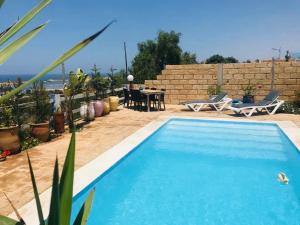 una piscina en un patio trasero con mesa y sillas en LES OLIVIERS en Oualidia