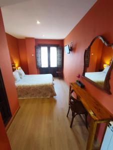 Habitación con 2 camas, escritorio y espejo. en Hotel Rural Pajarapinta, en Molinaseca