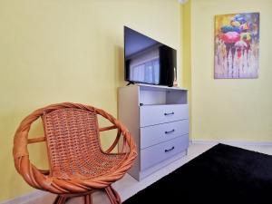 um quarto com uma cadeira, uma televisão e uma cómoda em Апартаменты MOON APARTMENTS - RIVER PARK em Almaty