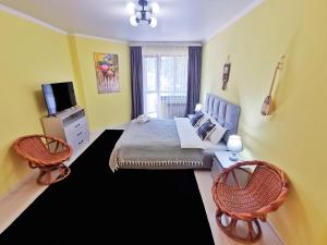 um quarto com uma cama com duas cadeiras e uma televisão em Апартаменты MOON APARTMENTS - RIVER PARK em Almaty