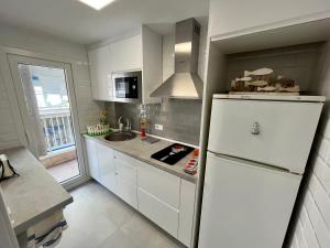 una cucina con armadietti bianchi e frigorifero bianco di Alquileres Morasol - RECIÉN REFORMADO ZONA CENTRO a Santa Pola
