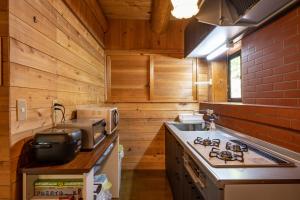 a kitchen with wooden walls and a stove top oven at ログハウスGrazzi in Nasu-yumoto