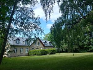 ein großes Haus auf einem grünen Hof mit Bäumen in der Unterkunft Apartment in Danmark -Petersminde Exclusive Apartments in Otterup