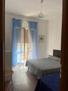 a bedroom with a bed and a window with blue curtains at La Casa del Professore in Nicotera Marina