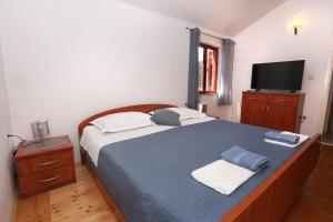 een slaapkamer met een blauw bed en een televisie bij Guest House Roses in Ston