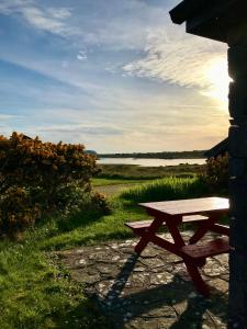 a wooden picnic table sitting next to a lake at Kilronan Cottage in Ballyconneely