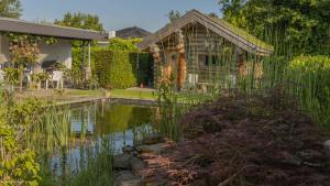 un jardin avec un étang en face d'une maison dans l'établissement Appartement Oase, à Klimmen