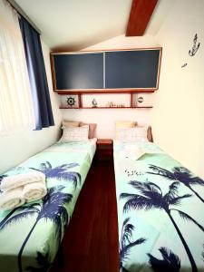 2 camas en una habitación con palmeras en Mobile home Nebo Luxus, en Klenovica