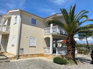 a large house with a palm tree in front of it at Apartman Palma in Vir