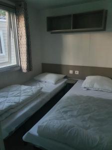 two twin beds in a room with a window at Camping 4 étoiles Le bois dormant in Saint-Jean-de-Monts +13 photos