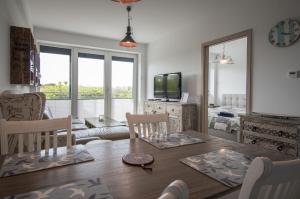 un salon avec une table, des chaises et une télévision dans l'établissement Apartament na wydmie - Darłowo, à Darłowo