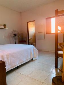 um quarto com uma cama branca e um espelho em Pousada Manga Rosa em Chapada dos Guimarães