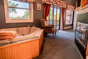 ein Badezimmer mit einer Badewanne, einem Stuhl und Fenstern in der Unterkunft Point Au Roche Lodge in Plattsburgh