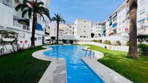 - une piscine dans une cour avec des palmiers et des bâtiments dans l'établissement Estudio Brisa en el centro de Nerja - South Costa, à Nerja