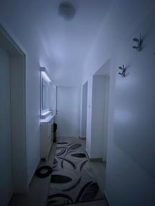 une salle de bains avec un couloir aux murs blancs et un tapis dans l'établissement Apartment in Shtip, à Chtip