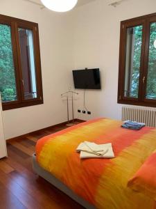 Schlafzimmer mit einem großen orangenen Bett und einem TV in der Unterkunft Le Palme - Appartamento elegante e moderno con garage privato in Padua
