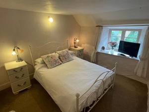 a bedroom with a white bed and a window at Minehead Forget me not Cottage in Minehead