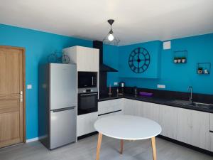eine blaue Küche mit einem weißen Kühlschrank und einem Tisch in der Unterkunft Gîte Les Tongs des Près, au cœur du Parc Normandie Maine in Livaie