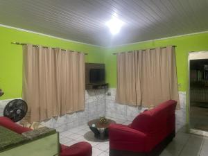 a living room with two red chairs and a tv at Casa - Prado - Bahia in Prado