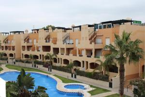 an apartment building with a swimming pool and palm trees at ÁTICO Paraíso Beach con piscina privada in Vera