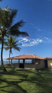 a kite is flying over a house with palm trees at Quintal da Praia in Prado