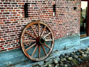 una rueda de carruaje de madera en el lateral de una pared de ladrillo en Burgemeestershof en Wetteren