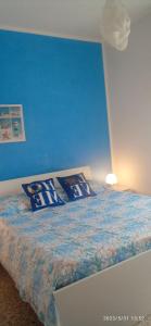 Un dormitorio con una pared azul y una cama con almohadas en Sogni nel Blu Favignana, en Favignana