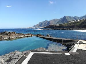 uma piscina de água azul junto ao oceano em La casa rosada (The pink house) em Tejina