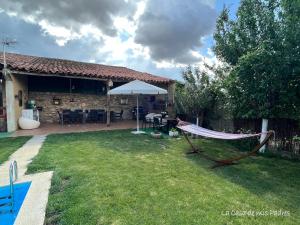 a hammock in the yard of a house at White Tree JARA - Casa Rural para grupos con piscina en Zamora in Rabanales