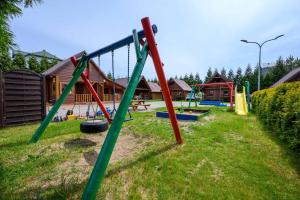 a playground with a bunch of swings in a yard at Domki nad morzem - Nevada in Darlowko