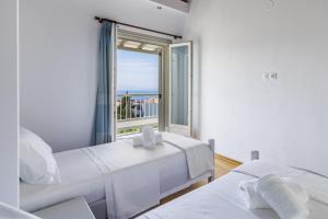 a white bedroom with two beds and a window at Villa Soultani in Glóssa +36 photos