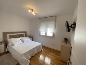 Habitación blanca con cama y espejo en Apartamento Arousa Mar en Villanueva de Arosa