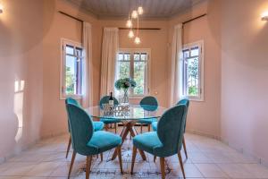 a dining room with a glass table and blue chairs at Sunset English Villas in Paralía