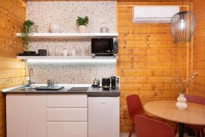 a kitchen with white cabinets and a wooden wall at Chillout Apartman Noszvaj in Noszvaj