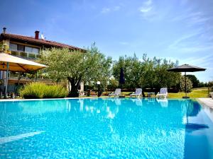 una gran piscina azul con sillas y sombrilla en Pansion Villa Margerita, en Poreč