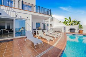 a swimming pool with white chairs and a house at Villa Torremimosas in Fuengirola