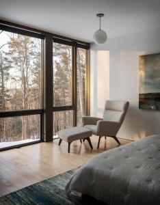 a bedroom with a bed and a chair and windows at Sterling Treehouse in Stowe