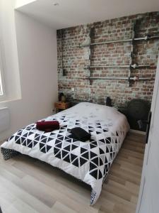 TonneinsにあるJoli 2 pièces Club Houseのベッドとレンガの壁がある寝室 +2枚の写真