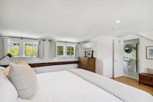 een slaapkamer met een groot wit bed en ramen bij The Village Farmhouse in Stowe